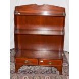 An early 20th century mahogany waterfall bookcase, cross banded incorporating two-drawers and raised