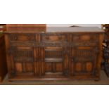 A 17th century style carved oak dresser base with three drawers and panelled cupboards, 168cm by