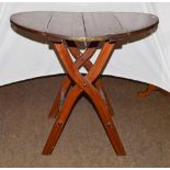 A Victorian pine coaching table of circular shape, folding on scissor supports, 80cm diameter