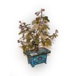 A Chinese cloisonne planter with hardstone tree. 33cm high, 25cm wide. Some pitting to the metal