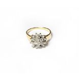 An 18 carat gold diamond cluster ring, the central raised round brilliant cut diamond within a