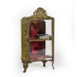A Gilt-Metal Mounted Miniature Display Cabinet, on scroll feet, with ribbon-tied love trophy finial,