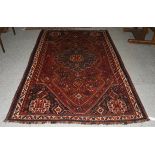 A Kashgai rug, the chestnut field with sky blue medallion framed by spandrels and ivory borders,
