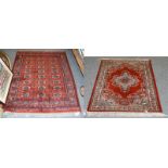 A machine made rug, the blood red field with central medallion framed meandering vine borders