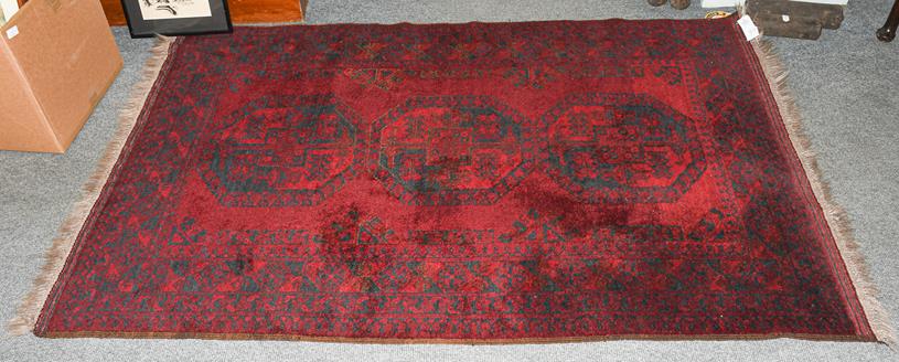 An Afghan Turkmen rug, the deep claret field with three elephant foot guls enclosed by multiple