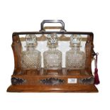 An oak three bottle tantalus with silver plated mounts (with key). Good condition. Locking mechanism