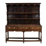 A George III Oak Open Dresser and Rack, 3rd quarter 18th century, the bold cornice above a wavy