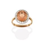 A Topaz and Diamond Cluster Ring, the oval cut topaz in a yellow rubbed over setting, within a