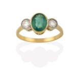 An Emerald and Diamond Three Stone Ring, the oval cut emerald in a yellow millegrain setting,