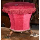 A Victorian rosewood octagonal workbox/stool with raspberry upholstery raised on three carved scroll