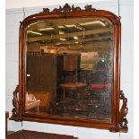 A large mahogany arched top over-mantle mirror with bevelled mirror plate, shell and scroll carved