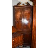 A George III mahogany standing corner cupboard with swan neck pediments, panelled doors and bone