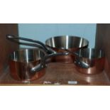 An assembled set of three graduated saucepans, copper on stainless steel, one (largest) stamped