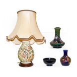 A quantity of Moorcroft pottery to include an Anemone pattern table lamp base, a clematis bottle