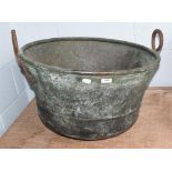 A 19th century copper cauldron with twin iron loop handles, 64cm wide. Handles heavily pitted. Dents