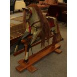 An early 20th century dapple grey rocking horse on trestle base, 119cm to the tip of the ears. Later