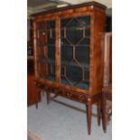 A 1920's mahogany veneered astragal glazed bookcase, fitted with three frieze drawers and raised