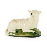A Creamware Model of a Sheep, circa 1800, naturalistically modelled recumbent on a green washed