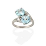 An Aquamarine and Diamond Ring, the round cut aquamarines diagonally set, in white claw settings, to