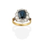 A Sapphire and Diamond Cluster Ring, the oval cut sapphire within a border of round brilliant cut