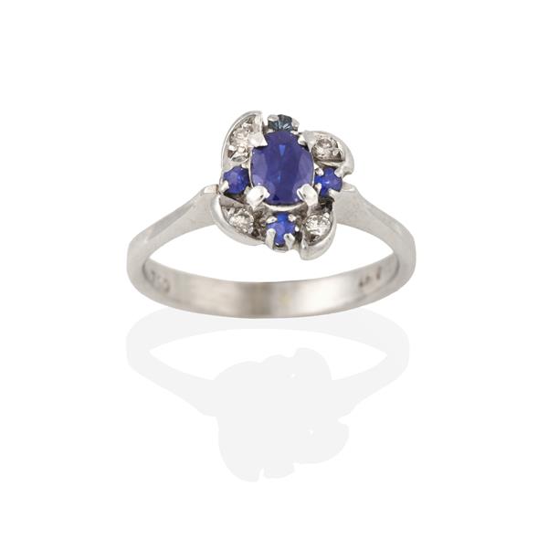 A Sapphire and Diamond Cluster Ring, the oval cut sapphire within an undulating border of eight-