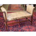 A carved mahogany window seat with original silk upholstery, with scroll arms and raised on square