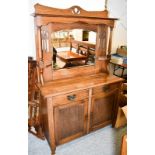 An Arts & Crafts mirror backed sideboard, the mirrored section over a double door cabinet, handles