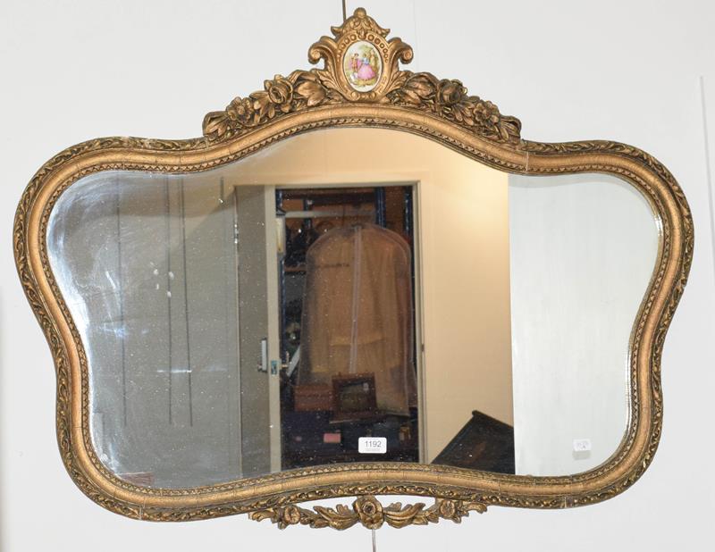 A gilt framed mirror surmounted by a painted porcelain roundel, 97cm by 73cm