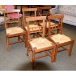 A set of five George III oak dining chairs, each with rush seats and including a carver chair