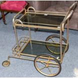 A circa 1950s French drinks trolley, gilt metal and smoked glass shelves, 70cm by 48cm by 85cm H