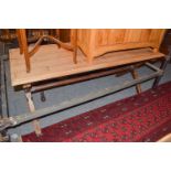 A pine refectory table on X form supports joined by a stretcher, with scrubbed top, 173cm by 74cm by
