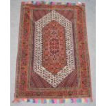 Afghan rug, the ivory lozenge field with an indigo medallion framed by deep terracotta borders,