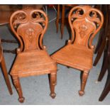 A pair of Victorian carved oak hall chairs, with balloon backs