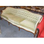 A 20th century carved walnut three-seater sofa, button backed and raised on scroll supports, 218cm