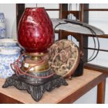 A Victorian brass oil lamp on a cast metal base with Ruby glass shade, together with a hanging oil