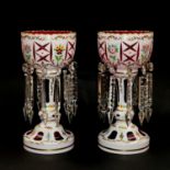 A pair of early 20th century cranberry table lustres with milchglas overlay, enamelled with