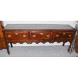 A George III crossbanded oak dresser base, fitted with three frieze drawers and scroll carved apron