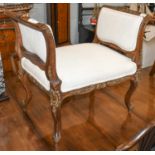 An early 20th century French carved walnut stool, with parcel gilding and raised on scroll supports,