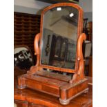 A Victorian mahogany toilet mirror, with carved scroll supports and a sliding compartment, 54cm by