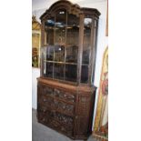 An intricately carved part-glazed Victorian oak bookcase cabinet, with arched top