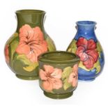 Three pieces of Walter Moorcroft Hibiscus pattern pottery, one vase one planter on a green ground
