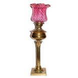 A Victorian brass Corinthian Column Oil lamp with cranberry glass shade, overall height including