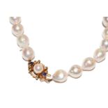 A cultured pearl necklace knotted to a 9 carat gold cultured pearl and sapphire clasp, length 69cm