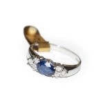 A 9 carat white gold sapphire and diamond ring, the oval cut sapphire flanked by trios of round