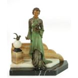 An Art Deco French Spelter Group, modelled as a young woman in a green and silver dress, holding a