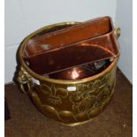 A Victorian embossed brass coal bucket with twin lion mask handles, decorated with a crest and