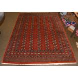 A 'Bukhara' rug, the deep terracotta field with rows of guls enclosed by multiple borders, 253 by