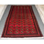 A Balouch rug, the crimson filed with rose of guls, enclosed by narrow borders, 242 by 134 cm