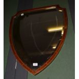 An Edwardian Sheraton revival inlaid mahogany wall mirror of shield form and with bevelled