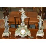 A green onyx and spelter figural striking mantle clock with garniture